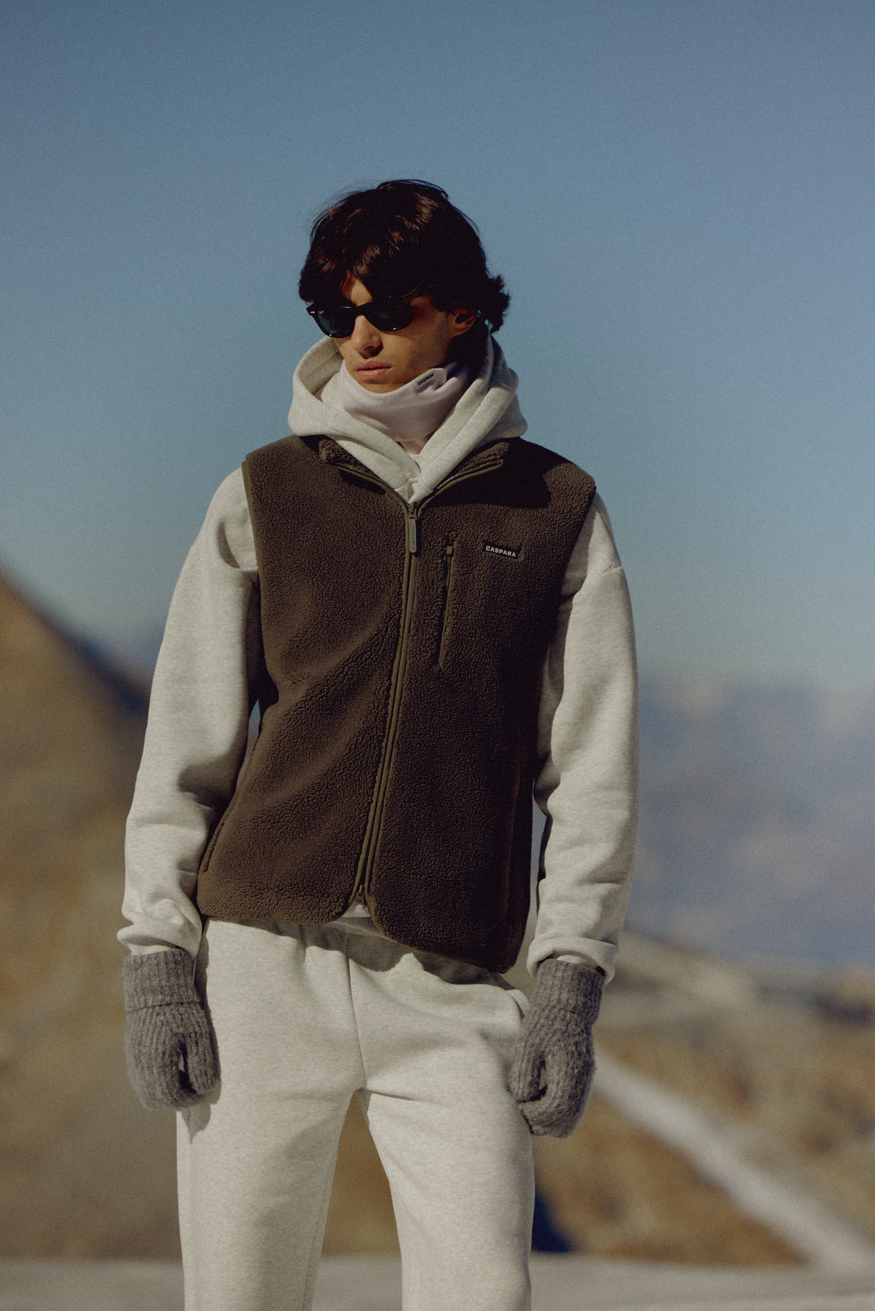 Man wearing a khaki CASPARA Cloudfleece vest in a mountain landscape.